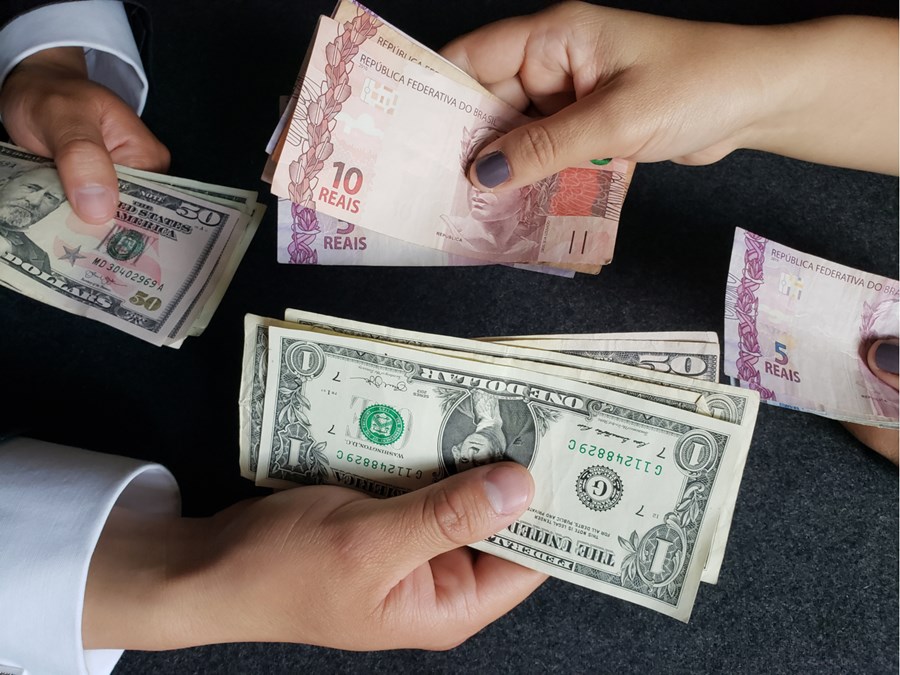Notas de real e dólar sendo trocadas