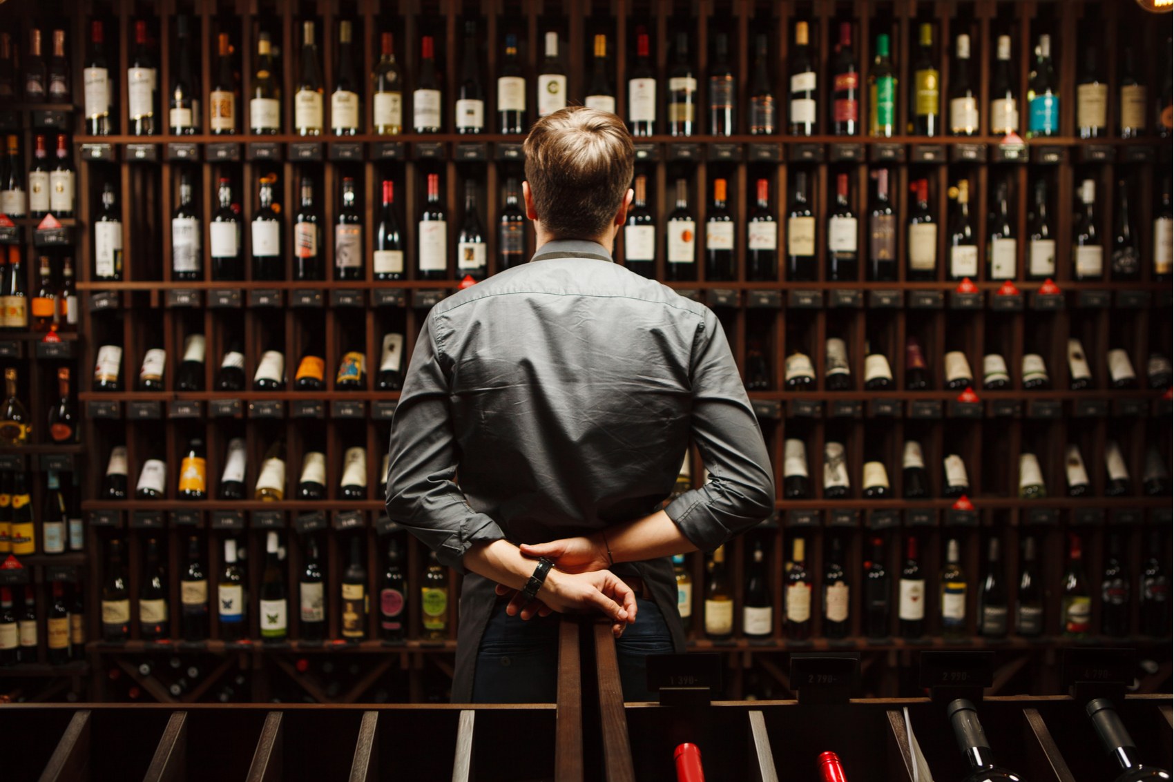 Sommelier em frente a uma estante com garrafas de vinho