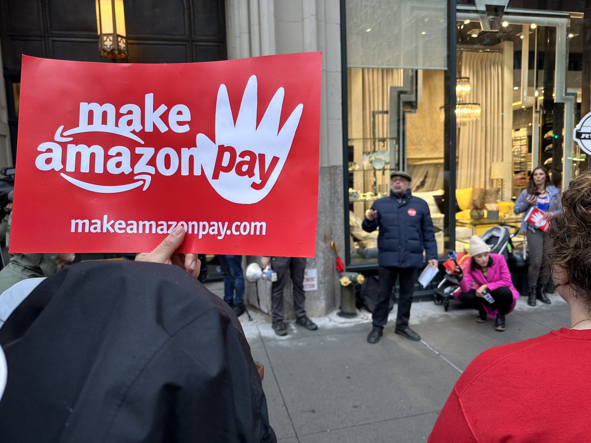 Manifestantes levantam cartazes com a frase "Faça a Amazon Pagar", na tradução para português. Foto: Redes sociais