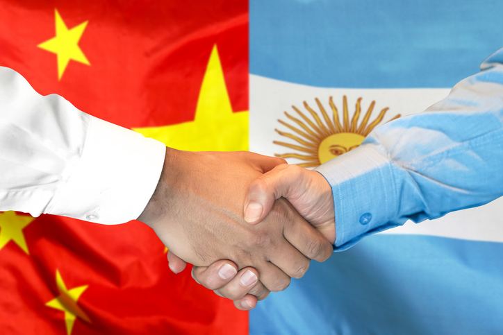 Foto de aperto de mãos com bandeiras de China e Argentina ao fundo (Getty Images)