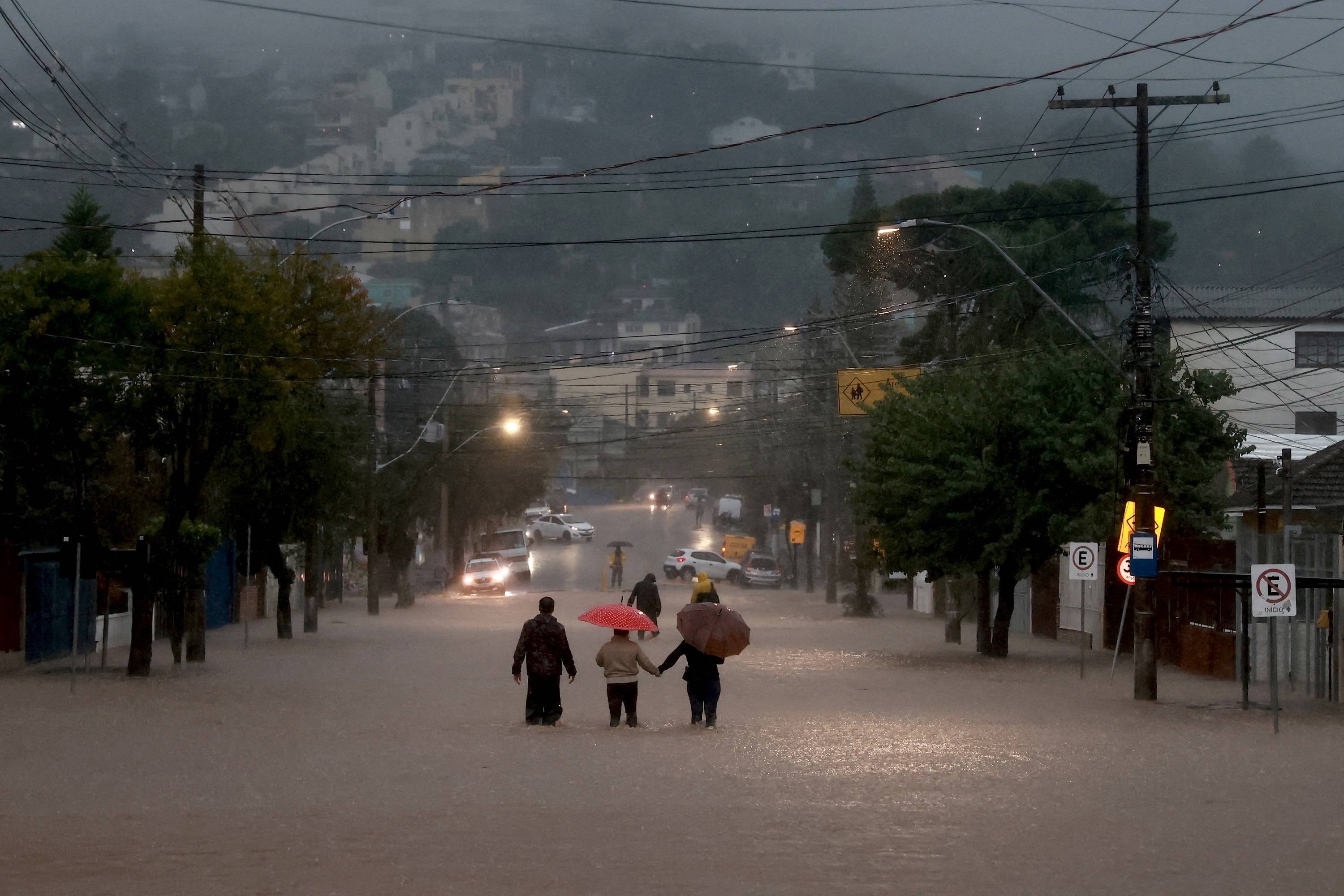 Moradores de bairro de Cavalhada, em Poro Alegre, caminham pela enchente (Foto: Diego Vara/Reuters)