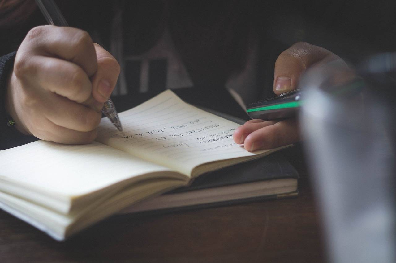 mão escrevendo com uma caneta em um caderno