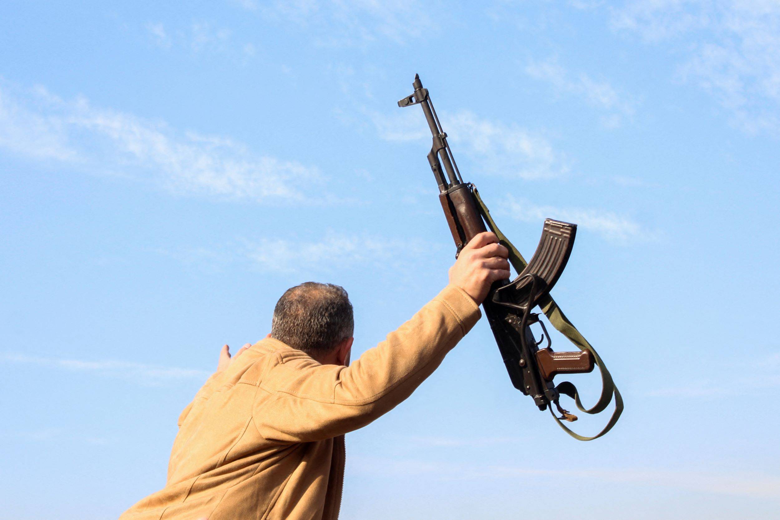 A man holds a weapon as they celebrate after Syrian rebels announced that they have ousted President Bashar al-Assad, in Damascus, Syria December 8, 2024. REUTERS/Firas Makdesi