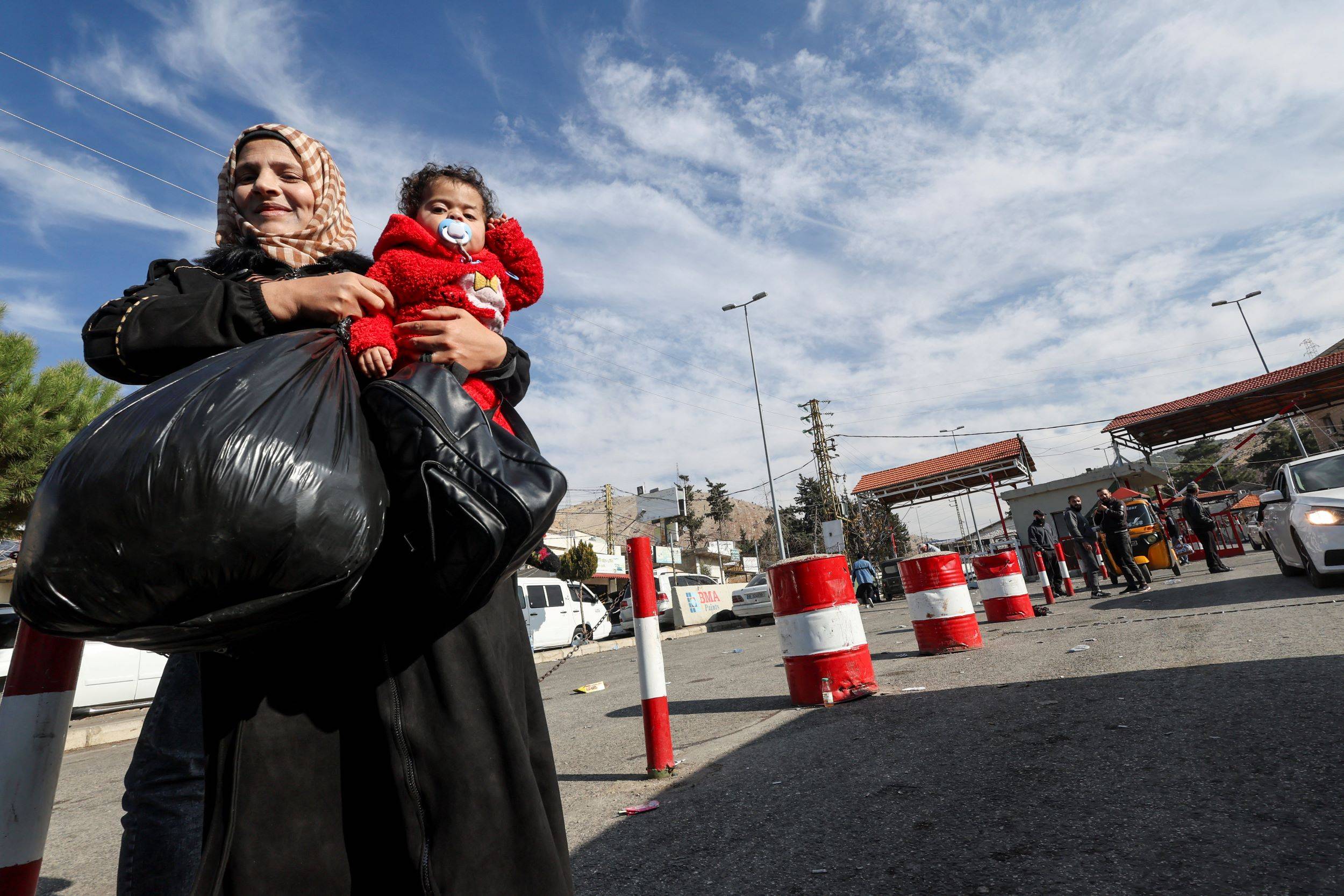 Mulher leva criança no colo na fronteira entre o Líbano e a Síria, em Masnaa, após a saída de Bashar al-Assad da presidência síria, em 8 de dezembro de 2024. Foto: REUTERS/Amr Abdallah Dalsh