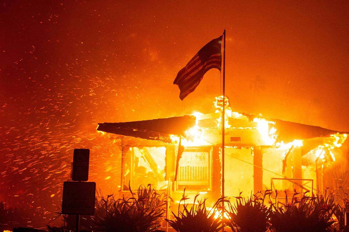 Bandeira dos EUA tremula enquanto o fogo consome uma estrutura durante a queima do incêndio Palisades em meio a uma tempestade de vento no lado oeste de Los Angeles, Califórnia, EUA, em 7 de janeiro de 2025. REUTERS/Ringo Chiu.

