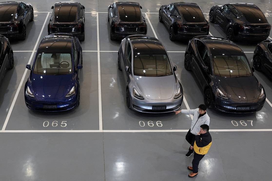 FOTO DE ARQUIVO: Pessoas passam por veículos elétricos da Tesla (EV) no centro de entrega da montadora em Pequim, China, em 8 de janeiro de 2025. REUTERS/Florence Lo/Foto de Arquivo.


