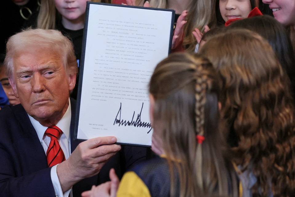 O presidente dos EUA, Donald Trump, exibe uma ordem executiva assinada que proíbe meninas e mulheres trans de participar de esportes femininos, na Sala Leste da Casa Branca em Washington, EUA, em 5 de fevereiro de 2025. REUTERS/Leah Millis.

