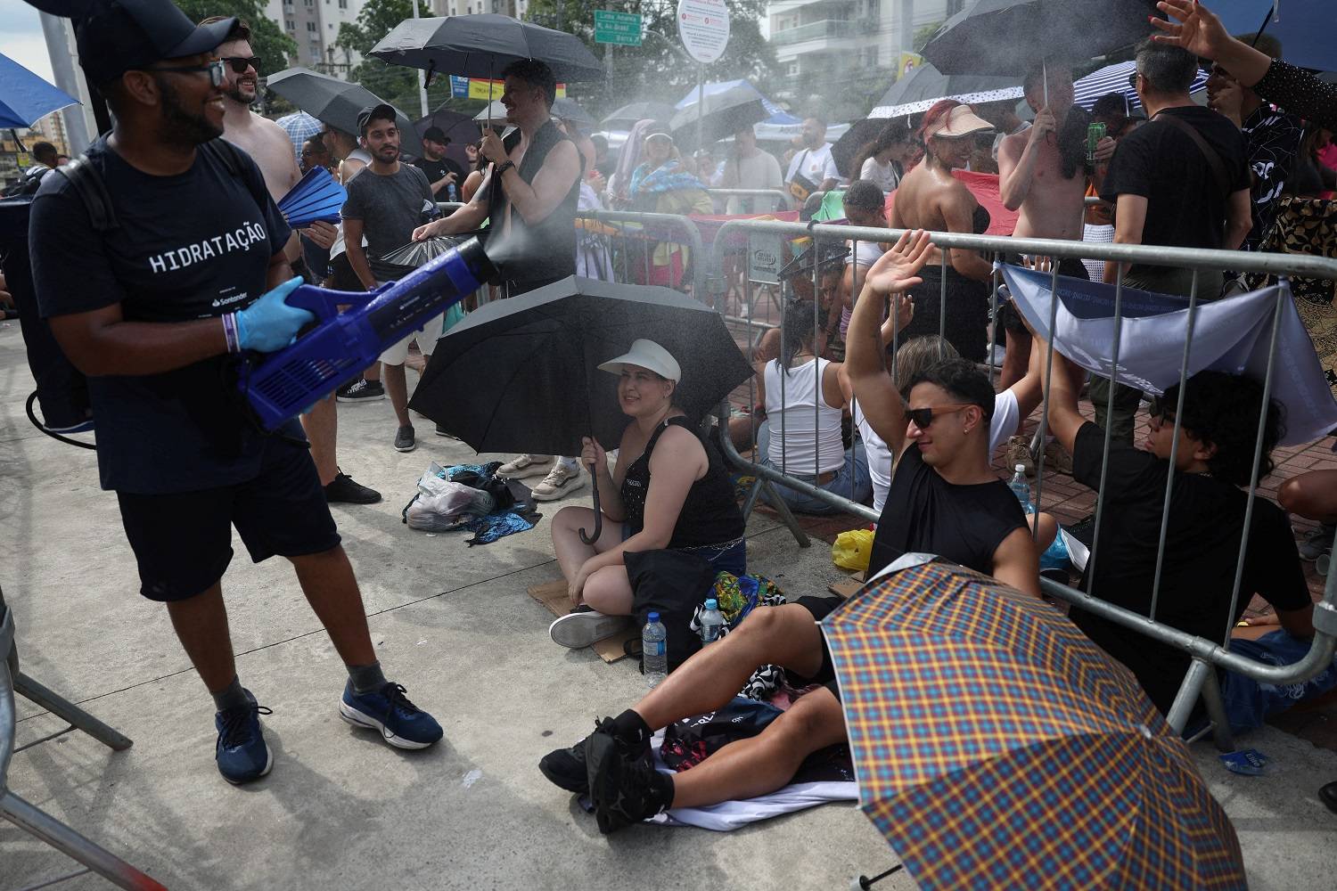 Fãs recebem água pulverizada para se refrescar do calor, enquanto aguardam em uma fila antes do show da cantora Shakira, em meio a altas temperaturas no Rio de Janeiro, Brasil, 11 de fevereiro de 2025. REUTERS/Pilar Olivares.

