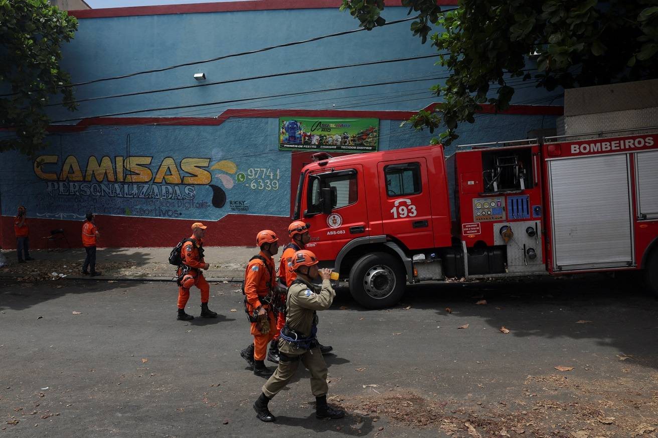 Bombeiros se reúnem do lado de fora de uma fábrica de roupas que estava produzindo fantasias para as celebrações de Carnaval, após um incêndio no Rio de Janeiro, Brasil, em 12 de fevereiro de 2025. REUTERS/Ricardo Moraes