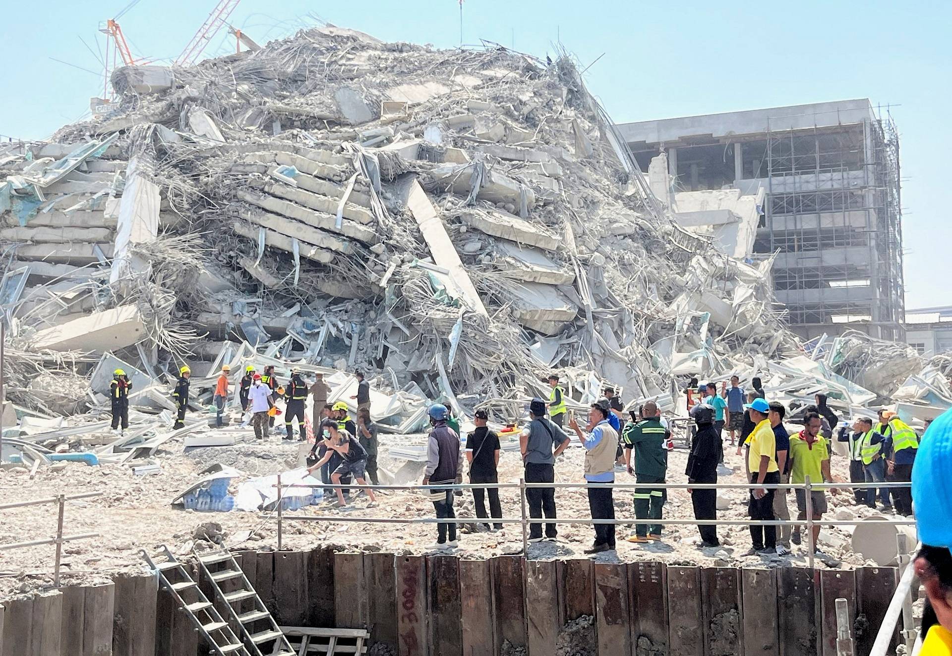 Pessoas ficam perto de um prédio que desabou após um forte terremoto atingir o centro de Mianmar na sexta-feira, disseram serviços de monitoramento de terremotos, que também afetou Bangkok, com centenas de pessoas saindo de prédios na capital tailandesa em pânico após os tremores, em Bangkok, Tailândia, 28 de março de 2025. REUTERS/Ann Wang