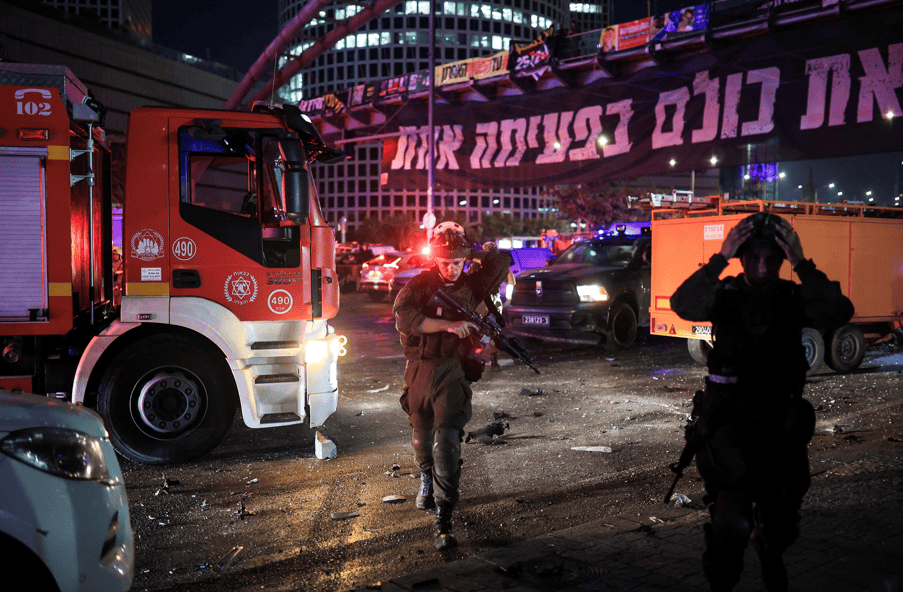 Policiais caminham enquanto socorristas trabalham em um local atingido por um ataque de mísseis do Irã contra Israel, em Tel Aviv, 14 de junho de 2025. REUTERS/Itai Ron