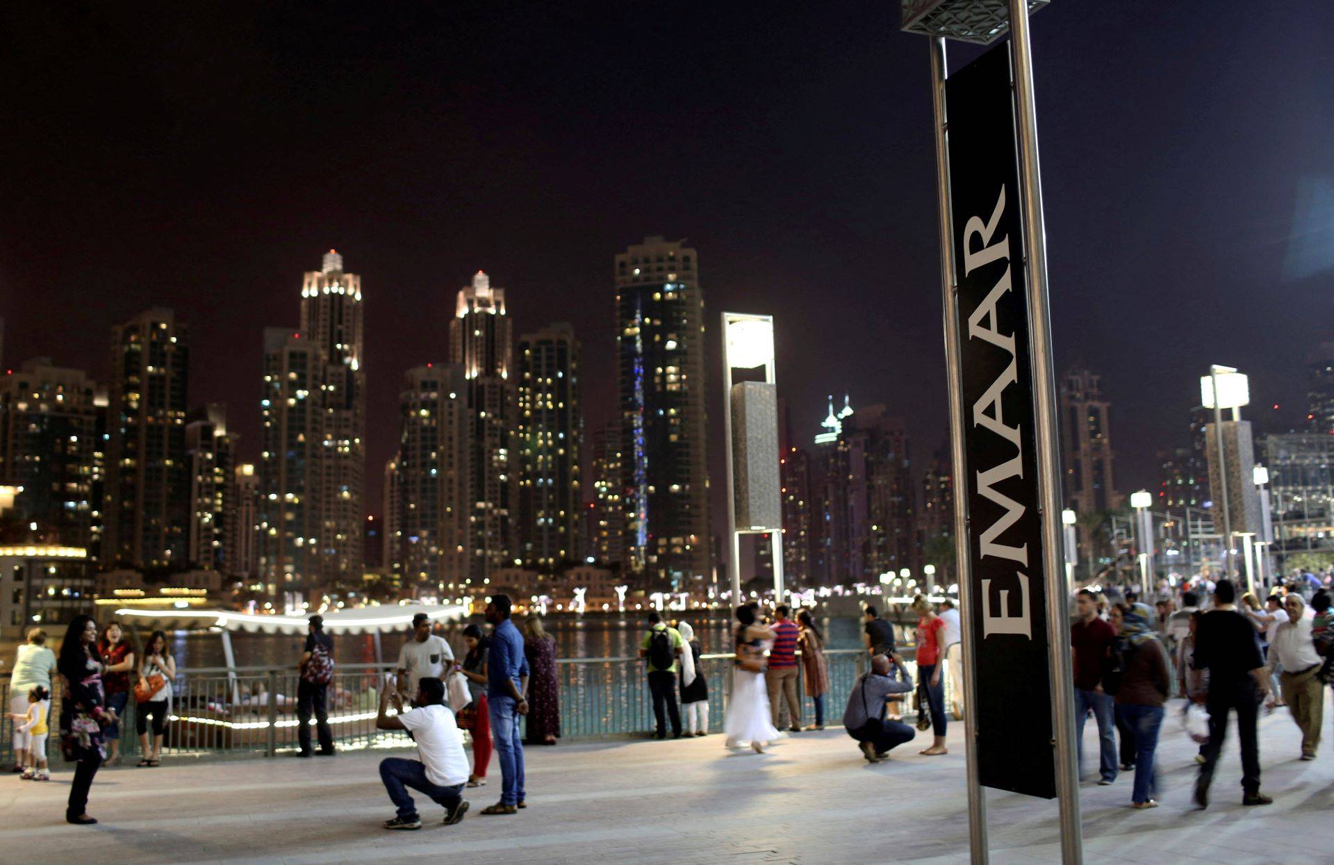 Pessoas tiram fotos perto de uma placa da Emaar em frente ao Dubai Mall - 15/03/2024 (Foto: REUTERS/Ahmed Jadallah)