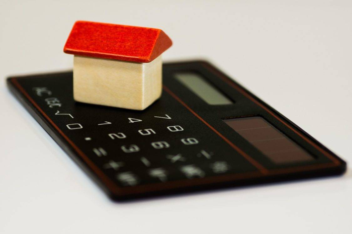 Miniatura de casa sobre calculadora faz referência a custos do consórcio