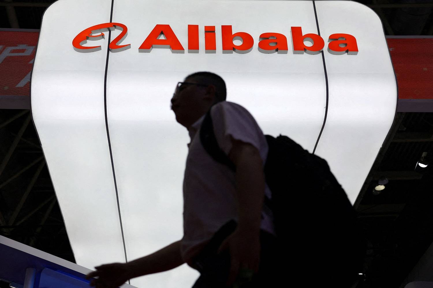 Um homem passa pelo logo da Alibaba exibido em seu estande durante a China International Supply Chain Expo em Pequim, China 16/07/2025 (Foto: REUTERS/Florence Lo)