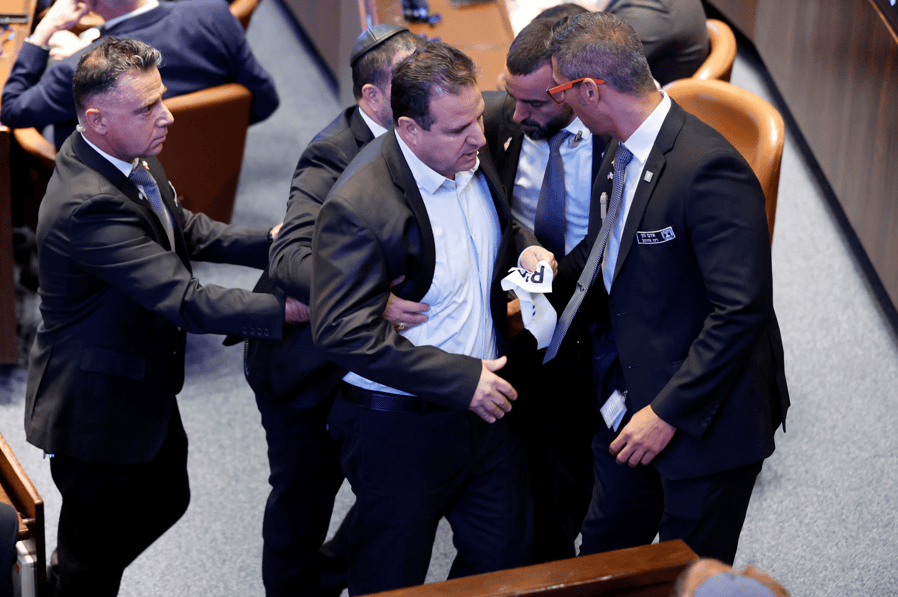 O membro do Knesset, Ayman Odeh, é retirado do plenário após levantar uma placa enquanto o presidente dos EUA, Donald Trump, discursava no Knesset, o parlamento israelense, em 13 de outubro de 2025, em Jerusalém. Chip Somodevilla/Pool via REUTERS