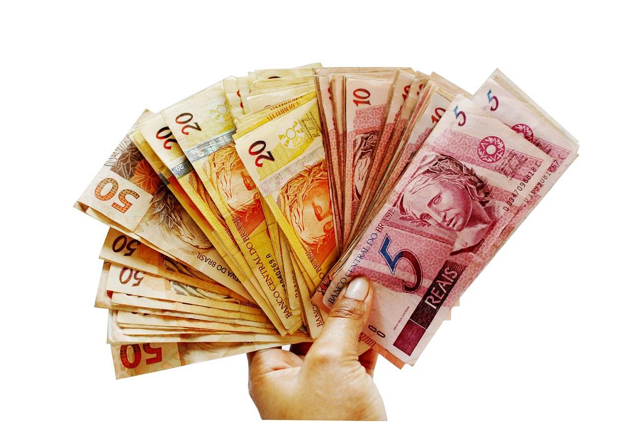 mão segurando cédulas de reais