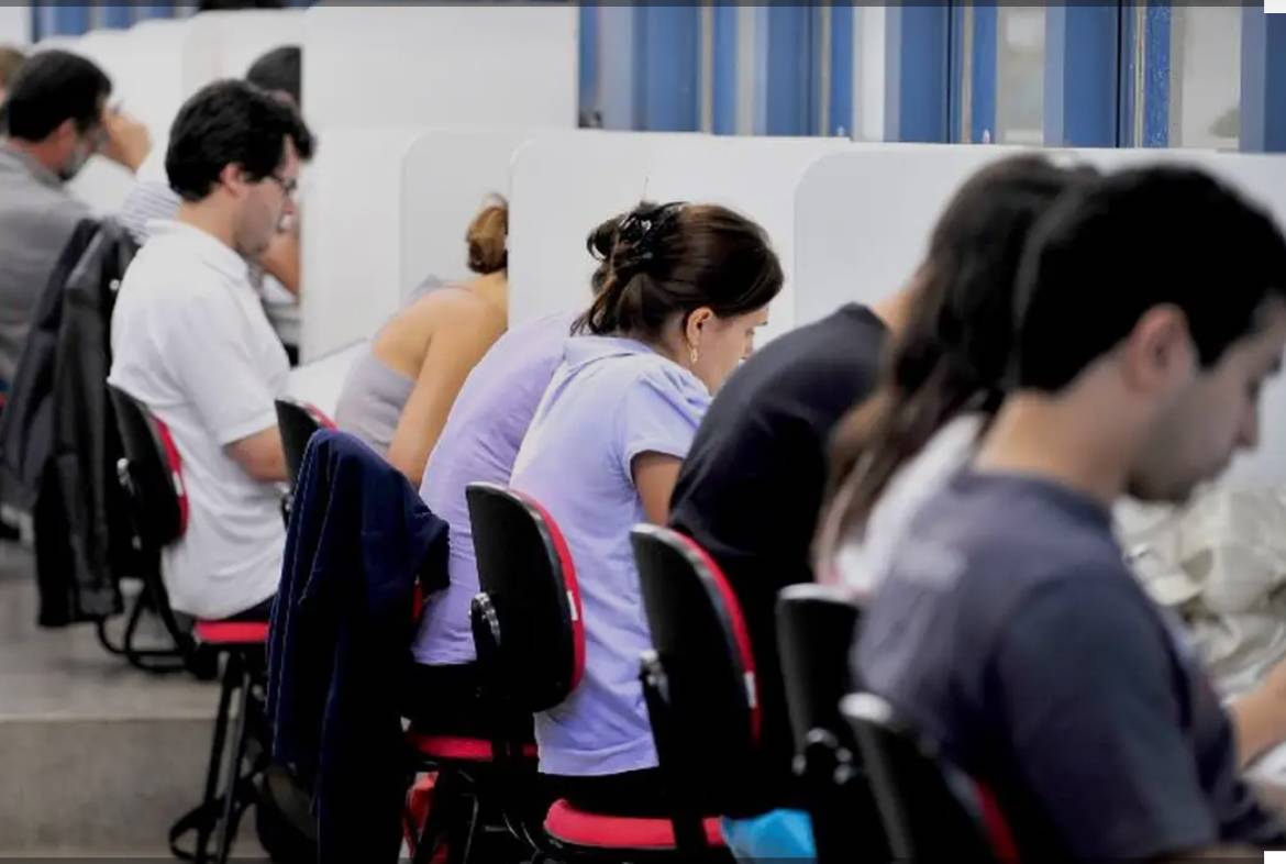 Pessoas em uma sala prestando prova para concurso público