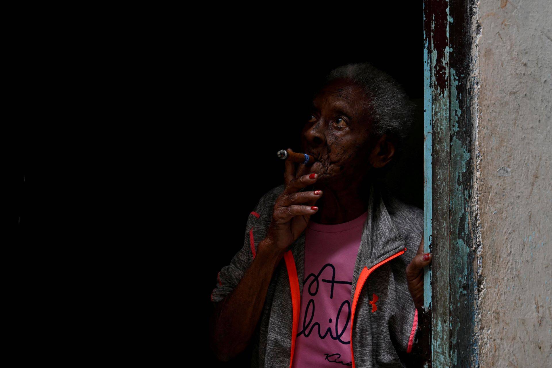 Idosa fuma um charuto na porta de sua casa em Havana 30/01/2026 (Foto: REUTERS/Norlys Perez)