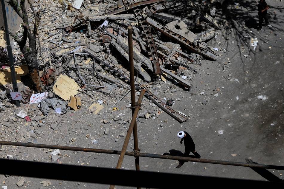14 de abril de 2026 - Um homem caminha ao lado dos destroços de um prédio residencial em Teerã atingido por ataques no dia 4 de março. Foto: REUTERS/Thaier Al Sudani