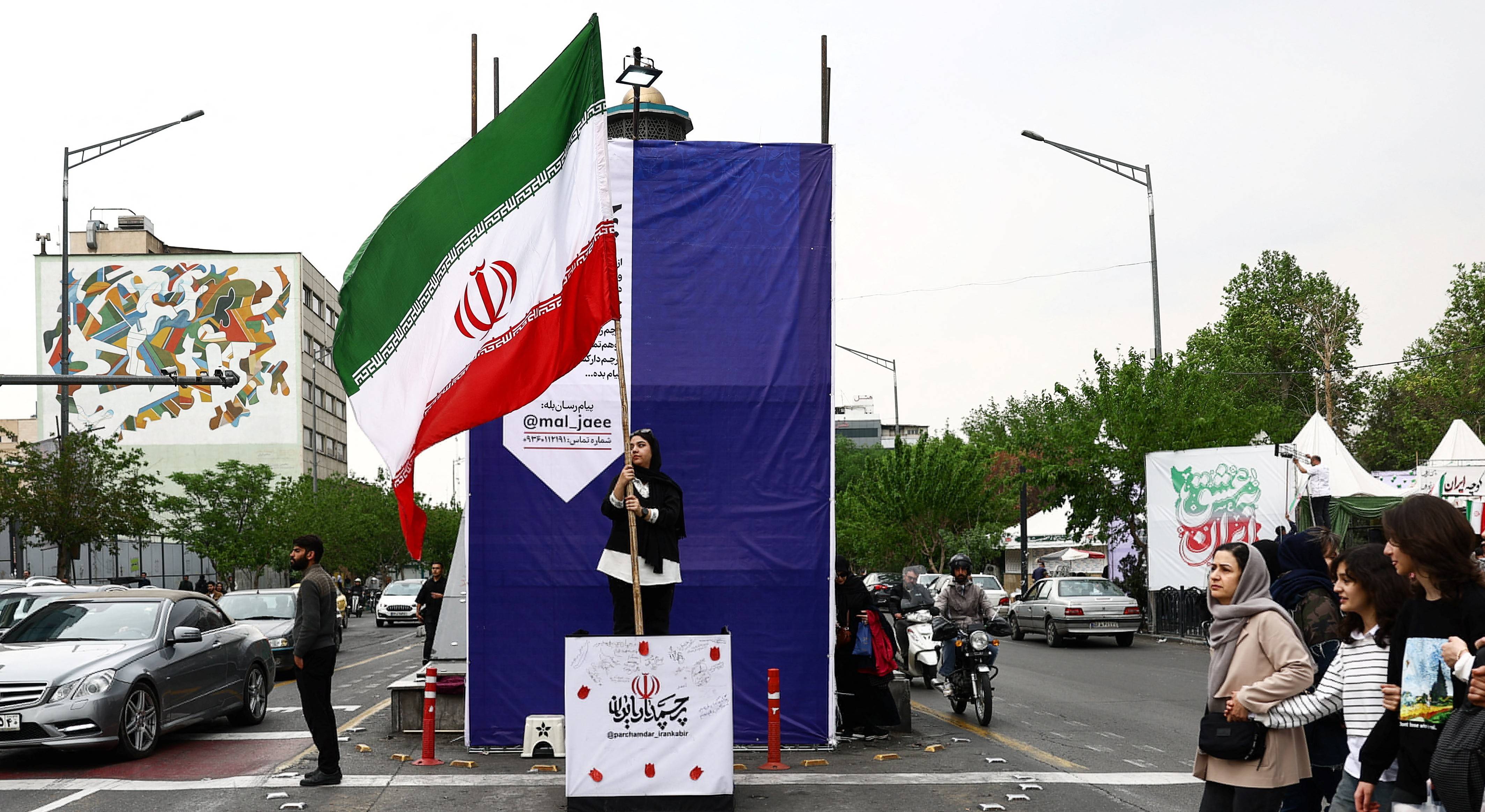 Mulher segura uma bandeira iraniana em uma rua, em meio a um cessar-fogo entre os EUA e o Irã, em Teerã, Irã, 20 de abril de 2026
Majid Asgaripour/WANA via REUTERS