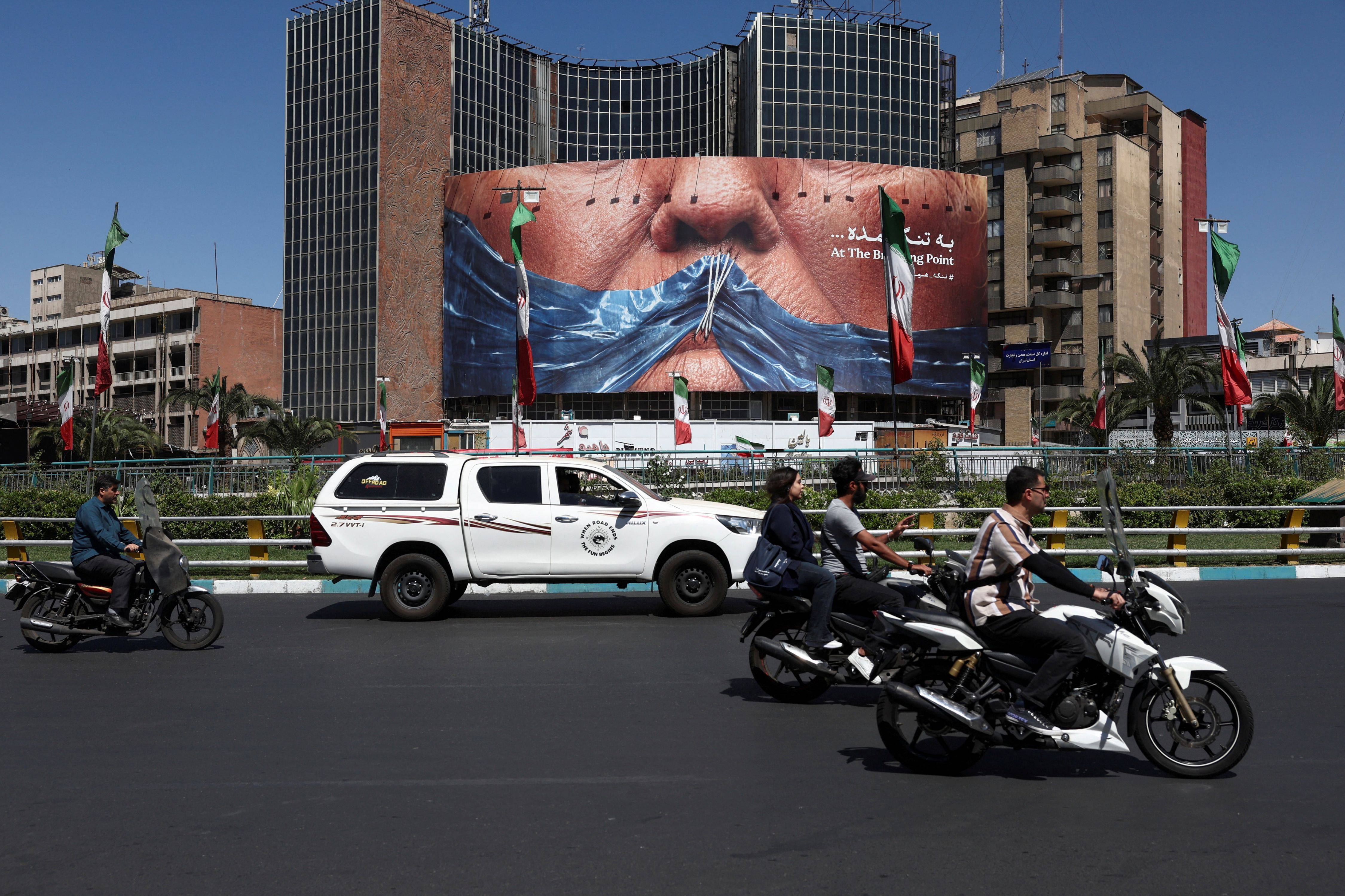 Pessoas passam por outdoor anti-EUA em Teerã 25 de maio de 2026 Majid Asgaripour/WANA via REUTERS